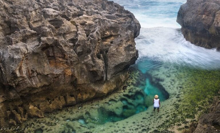 Aerial view of Kelingking Beach in Nusa Penida with turquoise waters and rugged cliffs.
