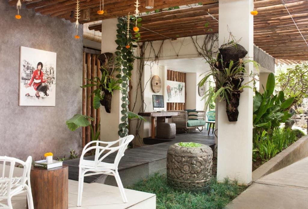 Open-air villa interior in Bali with tropical plants, wooden ceiling, and relaxed seating area