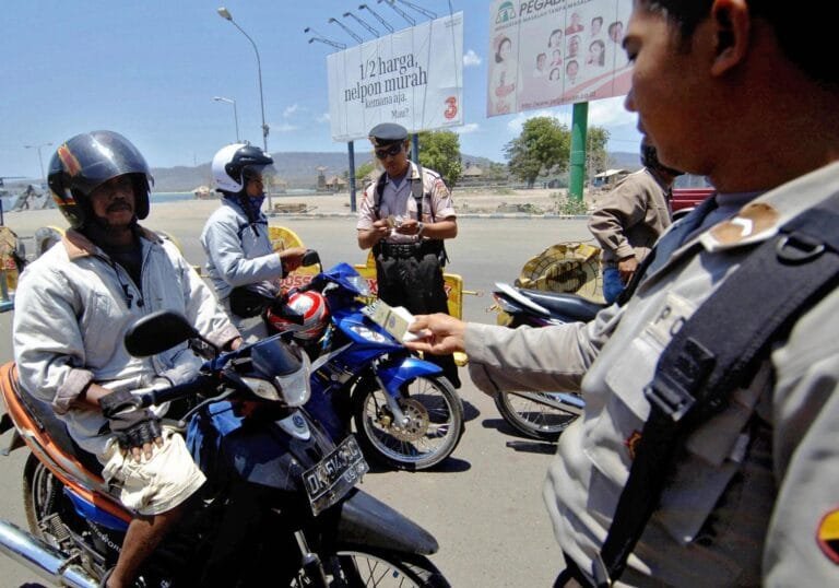 Tourist riding a scooter approaching a police checkpoint in Bali